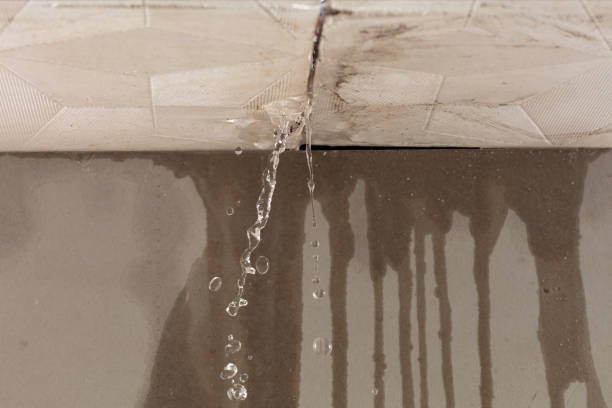 Active water leak dripping through a damaged indoor ceiling from roof failure.