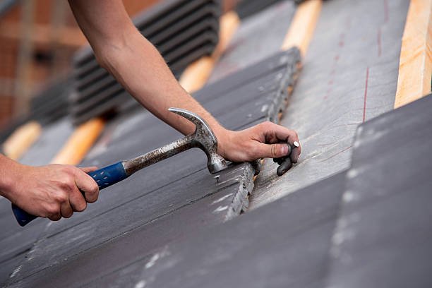 New Jersey roofing contractor repairing sloped slate tile roof leak points with a claw hammer.